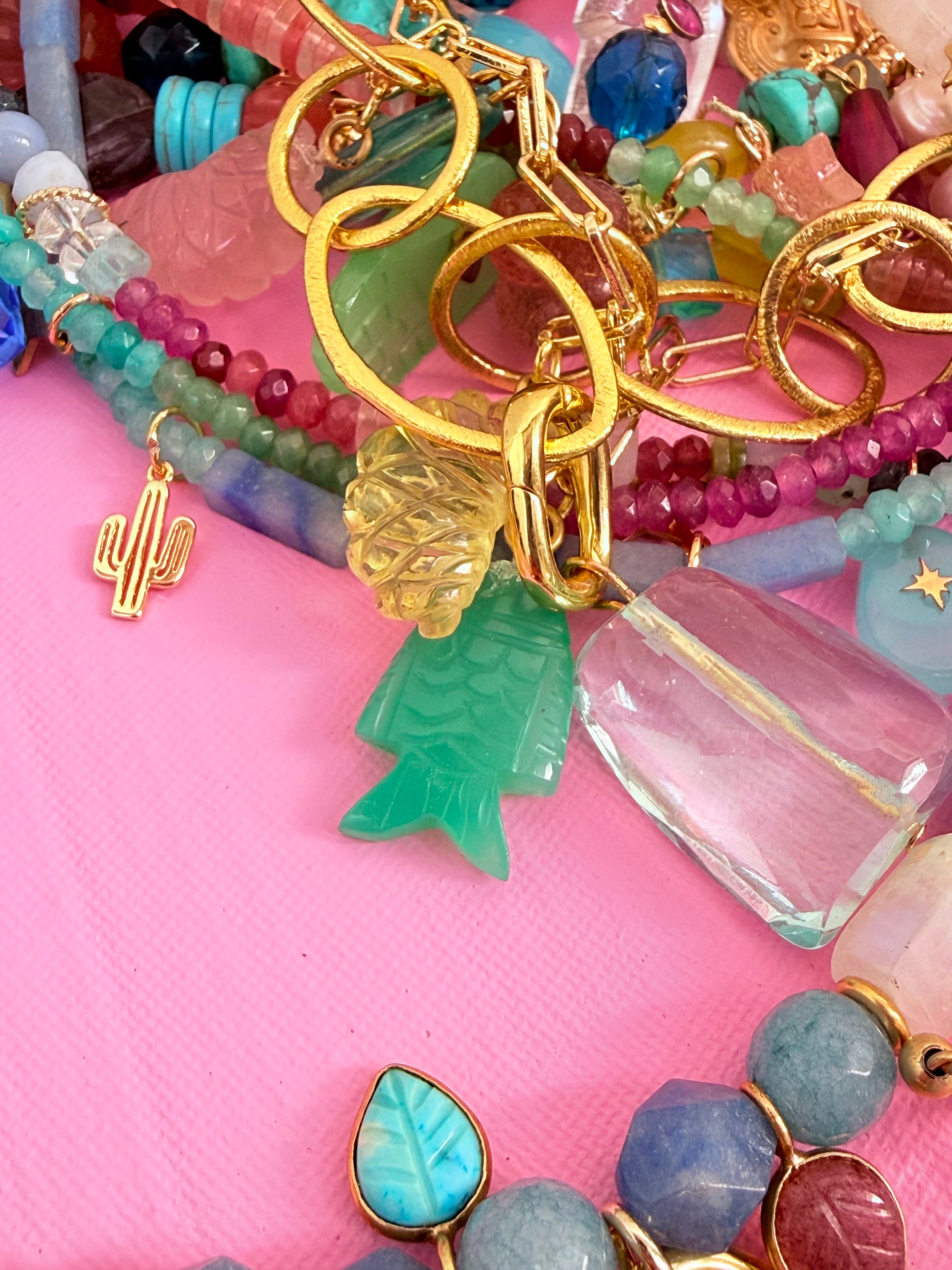 Colorful beaded jewelry with gold accents on a pink background
